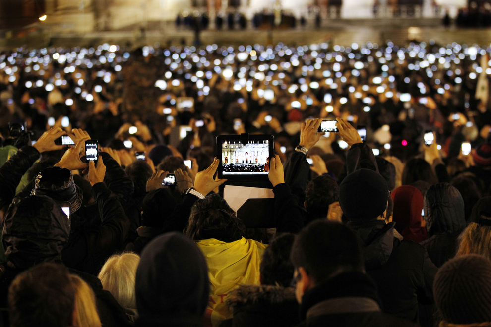 Des Catholiques prennent des photos avec leurs téléphones et tablettes du pape François nouvellement élu et présent sur le balcon de la basilique Saint-Pierre au Vatican.